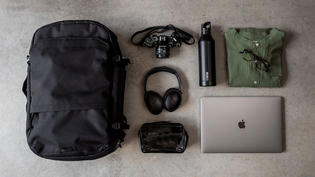 Pakt backpack with items for travel, including a laptop, camera, and headphones